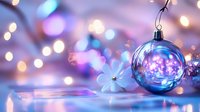 Magical glass Christmas ball ornament with purple and blue bokeh lights reflecting festive holiday atmosphere, delicate white flower on blurred background.