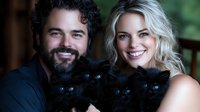 Happy couple holding adorable black kittens together, smiling warmly at camera in cozy home setting for family and pet lifestyle content.