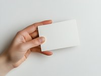 Female hand holding blank white business card on neutral background, suitable for branding, corporate identity, and marketing mockup designs.