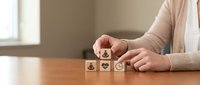 Woman arranging wooden blocks with healthcare symbols on desk representing medical services and wellness concepts for business presentations.