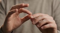 Close-up of male hands forming protective gesture, cupping palms together in caring pose. Concept of protection, safety, security and support.