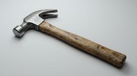 Vintage claw hammer with worn wooden handle on neutral background. Classic carpentry tool for construction, repair, and woodworking projects.