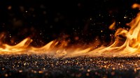 Dramatic low angle view of fierce flames spreading across dark textured surface with glowing embers and sparks against black background, creating intense atmospheric effect.