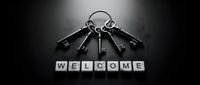 Bunch of vintage keys on a ring with letter tiles spelling WELCOME on dark background, monochrome concept of access and hospitality.