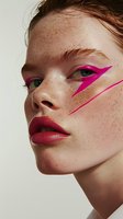 Young redhead model with natural freckles wearing bright pink geometric makeup and burgundy lipstick in creative beauty portrait against light background.