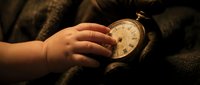 Child's hand holding vintage pocket watch with warm golden light, suitable for concepts of time, childhood memories, nostalgia, and heritage storytelling.