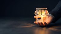 Hands holding glowing storefront icon against dark background, representing small business startup, entrepreneurship, retail shop opening, commerce growth, and online store launch concept.