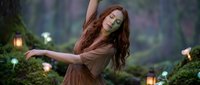Young Caucasian woman with long red hair dancing gracefully in enchanted forest setting with glowing lanterns and magical atmosphere for fantasy storytelling.