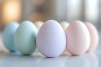 Pastel colored Easter eggs in soft focus arranged in row on white surface with gentle bokeh background creating dreamy spring holiday atmosphere.