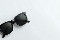 Classic black sunglasses with dark lenses on white background, minimalist fashion accessory composition with copy space for summer lifestyle and eyewear design.