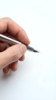 Hand holding silver ballpoint pen ready to write on white background isolated for business and office design projects.