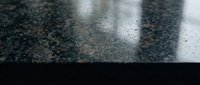 Wet asphalt road surface with white lane markings and water droplets after rain creating reflective pavement texture for transportation backgrounds.
