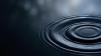 Water ripples creating concentric circles on dark surface with soft lighting and atmospheric background for meditation and wellness concepts.