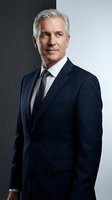 Professional mature Caucasian businessman in navy suit and tie with silver hair posing confidently against neutral background for corporate headshots.