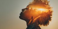Silhouette of African American woman with curly hair containing double exposure of urban sunset landscape and lone figure walking on path.