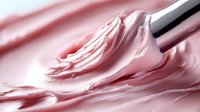 Pink cream or frosting being mixed with whisk creating smooth swirls and texture for baking dessert preparation culinary food styling background.