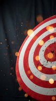Red and white dartboard target with glowing orange lights and sparks on dark background for business goals and achievement concepts.