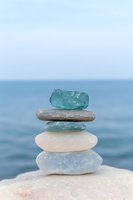 Balanced stack of smooth sea glass and beach stones creating zen meditation composition against calm ocean horizon for wellness and mindfulness concepts.
