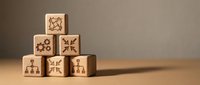 Wooden blocks stacked in pyramid formation with engraved symbols representing organization, hierarchy, and business structure for corporate training and management concepts.