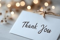 Elegant thank you note card with calligraphy text on white paper against soft bokeh lights background, tied with rustic twine string for heartfelt appreciation message.
