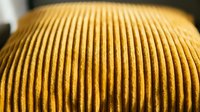 Close-up of yellow ribbed fabric texture with parallel grooves, suitable for textile, fashion, and design projects.