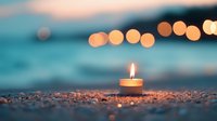 Glowing candle flame on sandy beach at dusk with soft bokeh lights in background creating peaceful meditation and wellness atmosphere.