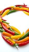 Colorful hot chili peppers arranged in a circular frame on white background. Red, yellow, orange and green fresh peppers for cooking, food styling, culinary design and recipe content.