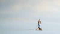 Young woman practicing yoga meditation in lotus pose on minimalist background with copy space for wellness and mindfulness concepts.