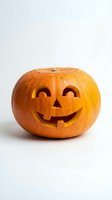 Carved orange pumpkin jack-o-lantern with glowing candle light isolated on white background for Halloween decoration and autumn seasonal design.