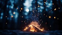 Campfire burning brightly in dark forest with glowing embers and sparks flying upward creating magical atmosphere for outdoor adventure camping.