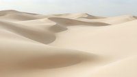 Vast desert sand dunes with smooth rolling waves and soft shadows under natural sunlight, suitable for travel, nature, and background design projects.
