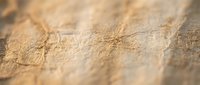 Warm golden sand texture with natural ripple patterns created by wind, showing fine grain detail and soft lighting for backgrounds and nature concepts.
