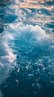 Turquoise ocean wave with sparkling water droplets and sunlight reflections creating magical bokeh effect. Dynamic splash captured in close-up view for nature backgrounds.