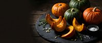 Autumn pumpkins and squash arranged on dark slate board with seeds, perfect for seasonal cooking and harvest decorating projects.