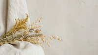 Dried golden wheat stalks and pampas grass arranged on neutral textured background for rustic home decor and natural botanical design projects.