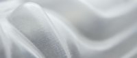 Smooth flowing white silk fabric with elegant curves and soft shadows creating luxurious textile waves for fashion and interior design projects.