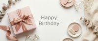 Happy Birthday flat lay with pink gift box, ribbon, eucalyptus, dried flowers, and ceramic decor on white background. Elegant greeting card.