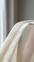 Close-up detail of beige linen fabric with visible stitching and natural texture. Soft neutral tones for interior design and textile projects.
