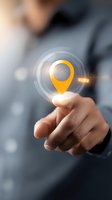 Glowing yellow location pin icon floating above businessman's finger with digital circles effect, representing modern GPS navigation and location services.