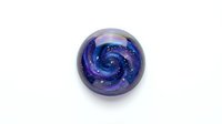 Glass marble with swirling galaxy pattern in purple and blue colors isolated on white background for jewelry making and craft projects.