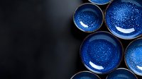 Handcrafted ceramic bowls with deep blue glaze and speckled texture arranged on dark background. Traditional Japanese pottery style with cosmic night sky effect.