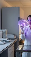 Female scientist examining glowing holographic brain model in modern laboratory for neuroscience research and medical technology advancement.