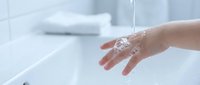 Clean water flowing over cupped hands in modern bathroom sink for hygiene and wellness routine.