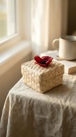 Wicker gift basket with red flower on linen table by sunny window creates cozy home atmosphere for special occasions and thoughtful presents.