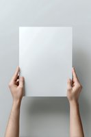 Female hands holding blank white paper sheet against neutral gray background, creating minimalist composition for mockup and design presentation purposes.