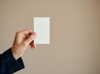 Hand holding blank white card against neutral beige background, suitable for business branding, stationery mockups, corporate identity design, and marketing presentations.