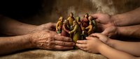 Diverse group of miniature people figures held safely in protective cupped hands representing community support, teamwork and social care concepts.