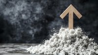 Wooden arrow pointing upward emerging from white powder pile on dark textured background symbolizing growth breakthrough and rising success in business.