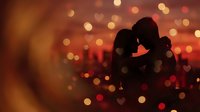 Romantic couple silhouette embracing against warm bokeh lights background creating intimate atmosphere for Valentine's Day and love concepts.