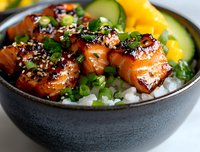 Glazed teriyaki salmon bowl with white rice, fresh cucumber, yellow bell pepper and green onions, garnished with black sesame seeds in dark ceramic bowl.
